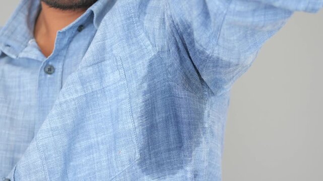 A man's underarm is soaked with sweat, highlighting the issue of excessive perspiration on a blue shirt