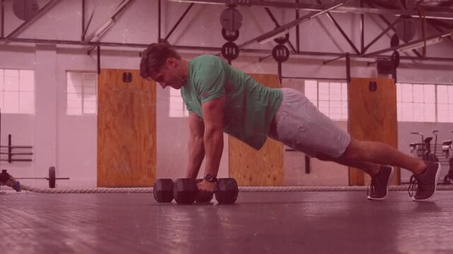 Mid-adult man gripping hex dumbbells, pushing to plank and performing alternating rows for fitness