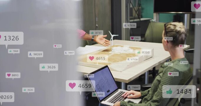 Senior man tapping tablet, gesturing while woman typing laptop, icons rising for design review