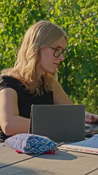 White female college student working on assignments in an outdoor setting.