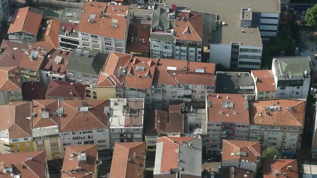 Aerial view of urban landscape with tightly packed buildings and red-tiled roofs, showing architectural density and city planning in motion
