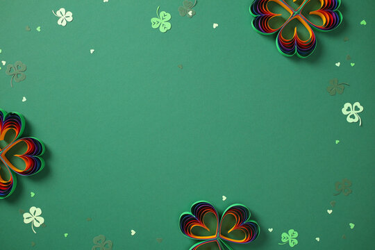 St. Patrick's Day banner with rainbow paper shamrocks on green background.