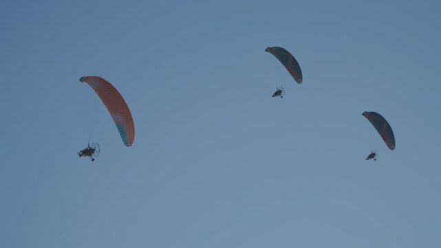 A group of paragliders are flying above the city of Vang Vieng in the afternoon.