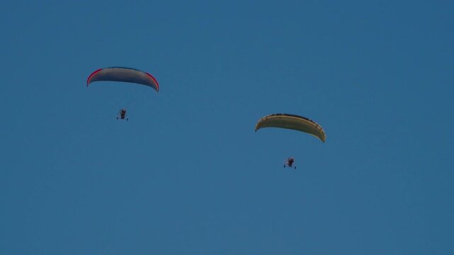 A pair of paragliders are flying above the city of Vang Vieng in the afternoon.