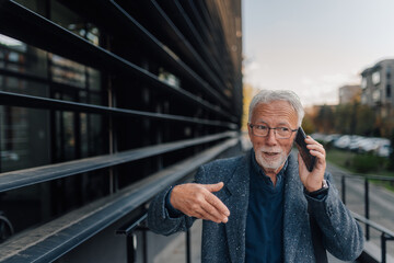 Senior businessman talking on mobile phone outdoors gesturing