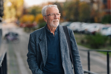 Mature businessman walking outdoors looking away smiling