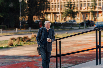 Senior man walking urban street with coffee