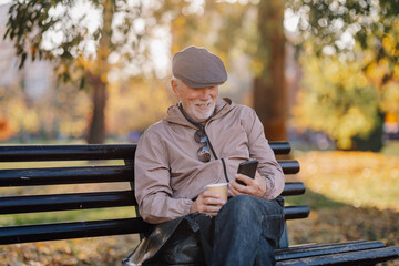 Senior man relaxing on park bench using smartphone