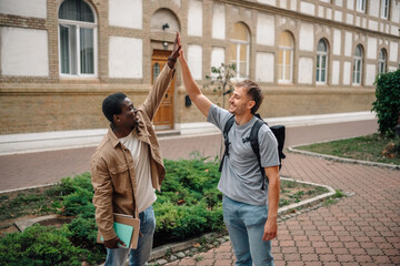 Two happy students giving high five celebrating success in university campus