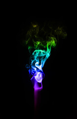 Fototapeta premium A delicate wisp of multicoloured smoke curling gracefully against a deep black background, creating an ethereal and minimalist atmosphere