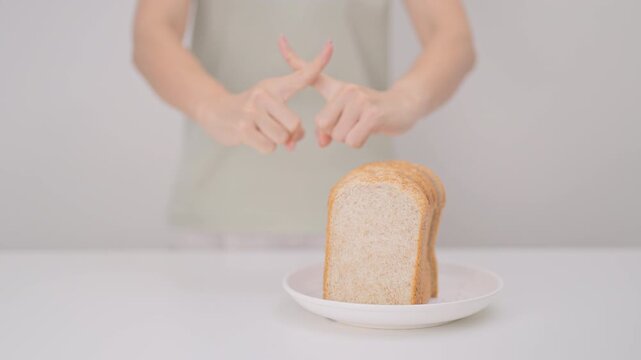 Unhappy woman showing Rejecting gesture and refusing to eat bread. concept of gluten intolerance, gluten sensitivity, carb loading concerns, or a disliking for unhealthy dietary habits