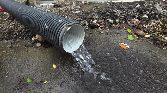 Water pouring from corrugated plastic pipe, storm sewer drainage runoff, rainwater management system, environmental pollution and erosion control during heavy rain