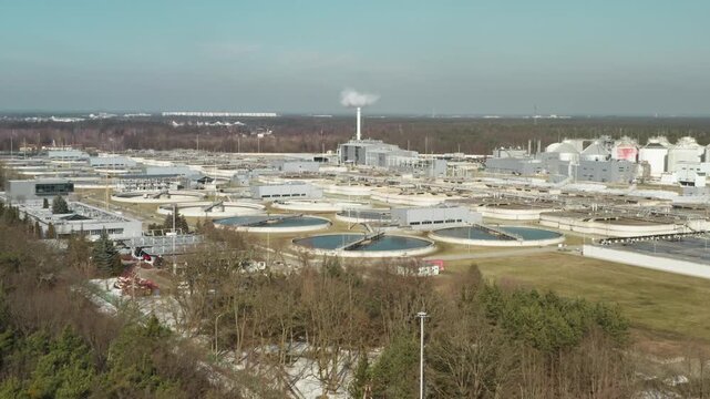 Large municipal utility complex operates thermal waste processing unit with chimney and sludge digesters to manage toxic pollution and produce sustainable energy from sewage sludge.