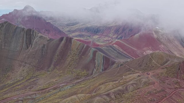 Aerial of Rainbow Mountain's colorful peaks under cloudy skies in Peru