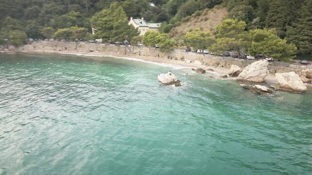 Cinematic 4K UHD drone orbit over a secluded Trieste cove on the Adriatic Sea, revealing rocky beach, turquoise water and forested shore&mdash;ideal for travel ads, openers.