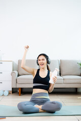 Fototapeta premium Smiling woman doing home fitness workout with tablet and headphones, showing thumbs up. Online training, healthy lifestyle, wellness and digital exercise concept.