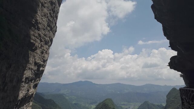 Panoramic mountain valley establishing framed by rocky cliff walls, establishing tilt up to rock face