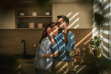 Loving couple sharing intimate morning moment in kitchen