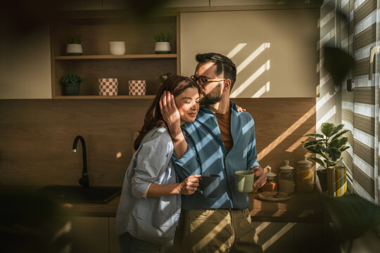 Loving couple sharing intimate morning moment in kitchen