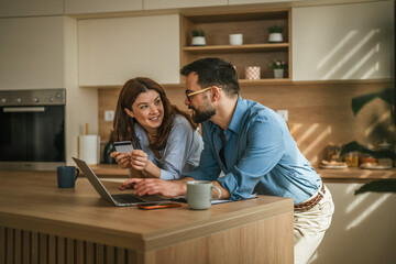 Obraz premium Couple managing home finances shopping online with credit card