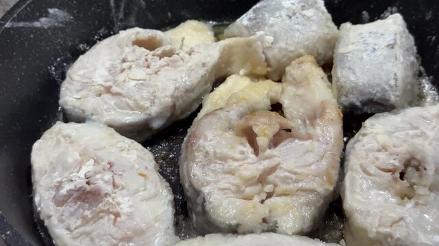 Breaded fish pieces in early cooking stage with flour crust in hot oil. Perfect for food blogs, cooking channels, and restaurant marketing video content.