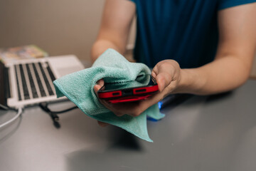 Close-up shot of person disinfecting smartphone screen with microfiber cloth, ensuring cleanliness...