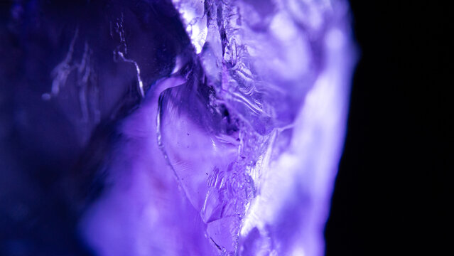 Macro photography of glowing purple crystal showing deep internal fractures and light