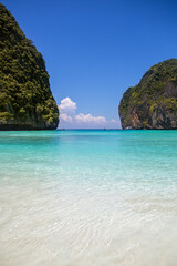 Fototapeta premium Panorama of Maya Bay on Koh Phi Phi Leh, Thailand. It's a beautiful, exotic shore with a crystal-clear turquoise waters. A pristine and tropical gulf enclosed by towering limestone karst cliffs.