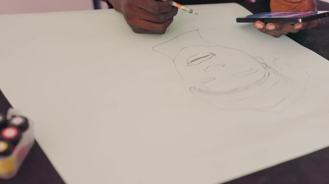 Black artist sketching portrait on paper using pencil and smartphone reference, dotted outline forming face, paint palette at table corner, closeup of darkskinned hands, calm focused studio