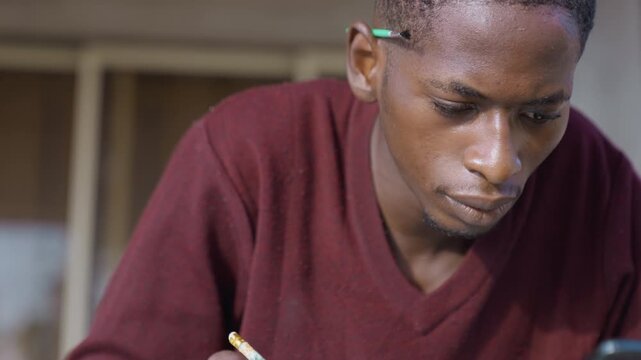 Closeup artist sketching with pencil, student studying proportions at desk frames show roles as student, illustrator, draftsman, portraitist, designer quiet studio light, maroon sweater, textured