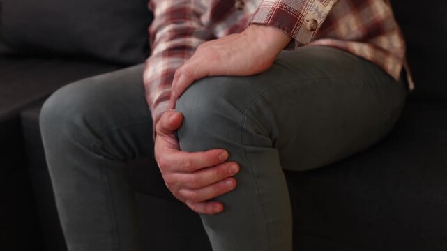 Man at home holding painful injured knee.