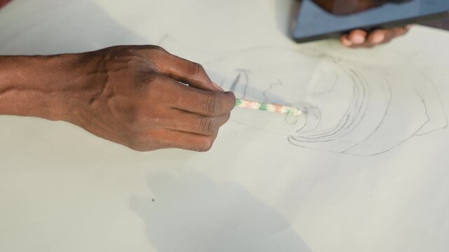 Hands tracing dotted pattern on paper phone used as reference fine brush tapping rhythmic dots closeup of fingers iterative design process textile design and illustration roles precision focus steady