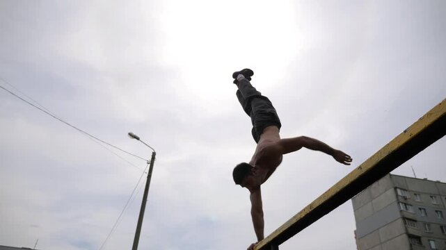 Sportsman performing dynamic workout on parallel bars, showcasing strength and control through progressive movements in an outdoor training environment with vibrant grass and exercise equipment
