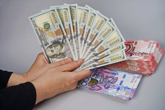 100 dollar bills and tenge banknotes in denominations of 5,000 and 10,000 on a paper background. Exchange rate, deposits, currency storage