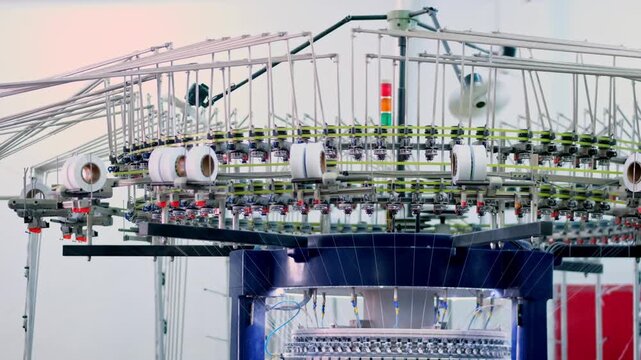 Automated circular knitting machine operating inside a modern textile factory. Professional industrial footage reflecting advanced textile technology and large scale manufacturing.