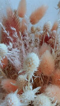 Close-up view of dried flower arrangement with fluffy lagurus and white thistles in boho style.