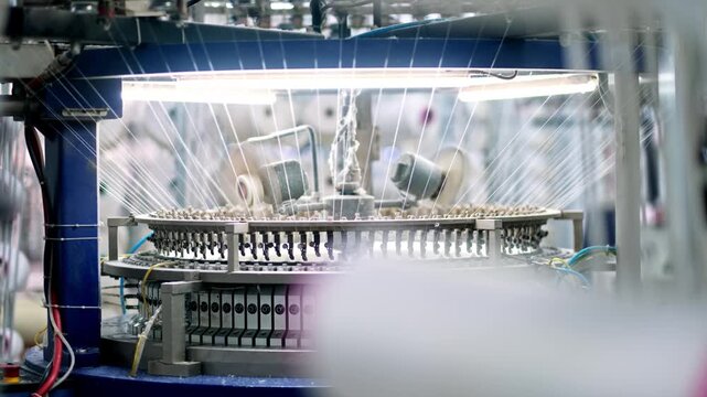 Automated circular knitting machine operating inside a modern textile factory. Professional industrial footage reflecting advanced textile technology and large scale manufacturing.