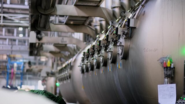 Professional industrial footage reflecting textile dyeing process and manufacturing discipline. Large dyeing machines aligned along a textile production line.