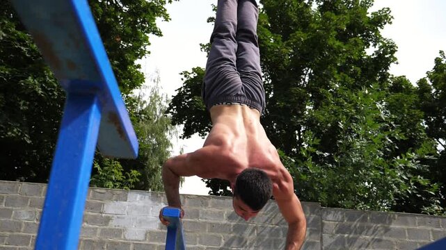 Sportsman performing dynamic handstand push-up training on parallel bars, showcasing strength and balance in a progressive workout sequence with vibrant greenery in the background