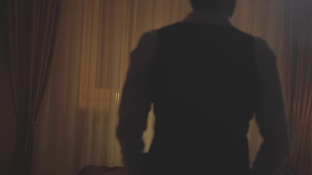 Blurred Silhouette mystery elegant man walking in dark ball room looking back. Vintage white shirt men's tweed vest 20s old roaring style. Sexy guy aristocrat gothic pensive king. fantasy black night.