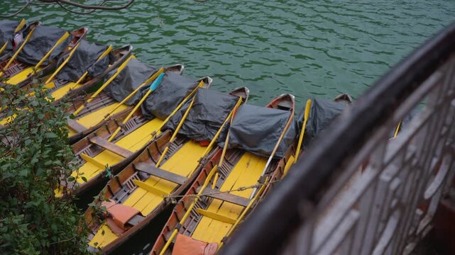 Overlooking balcony rail to colourful yellow wooden tourist boats floating in Nainital lake India