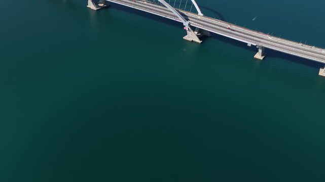 tunning aerial drone perspective of the Tseung Kwan O Cross Bay Link Bridge in Hong Kong, showcasing modern architecture, coastal transport infrastructure, and urban connectivity on a clear sunny day.