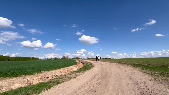 a loving couple walking through a field in summer