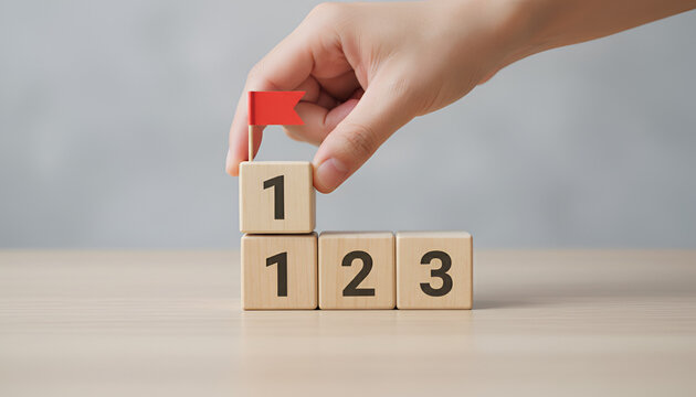 &ldquo;First Steps to Success: Red Flag on Top of Stacked Blocks numbered 1-3 on a Light Wood Surface&rdquo;

