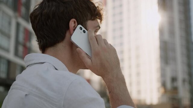 View from behind Caucasian business man communicate call corporate negotiation businessman talking mobile phone in city downtown unrecognizable businessman male guy talk smartphone calling outdoors