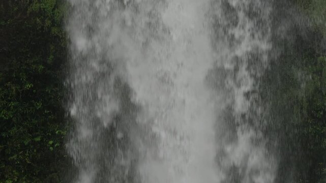Slow motion view of middle section of large cascade as it is falling down from large heights making vapor and steam in the surrounding air.