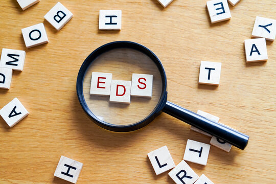EDS, mental health and medicine concepts. Wooden letters with a magnifying glass on a wooden background