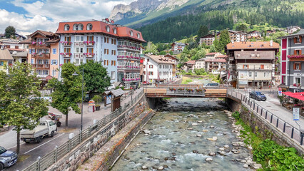 Fototapeta premium 15 july 2024, Moena, Italy. Aerial, bird view, drone view of Moena, a picturesque village in the Italian Dolomites during summer with Avisio river. Colorful houses, beautiful tourist travel destinati