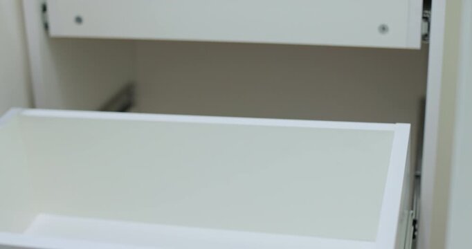 Handyman installing and adjusting drawer slide mechanism in contemporary kitchen. Furniture installation.