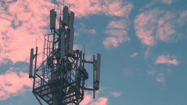 Equipment of Mobile Operator, Cellular GSM tower with 3g, 5g Transmitter Close-up, Cell Tower , Mobile Communication and Time Lapse of Pink White Clouds in the Blue Sky Aerial View.